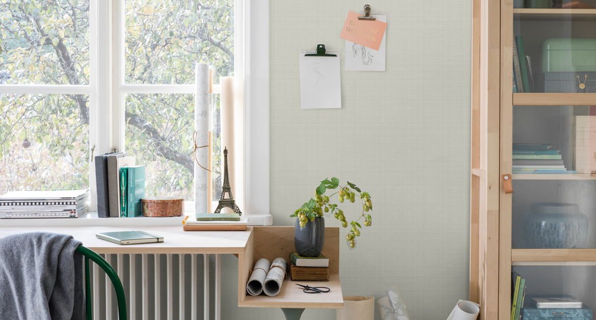 Hemmakontor med skrivbord och bokhylla i trä och ljusgrön tapet. Inspirationsbild.