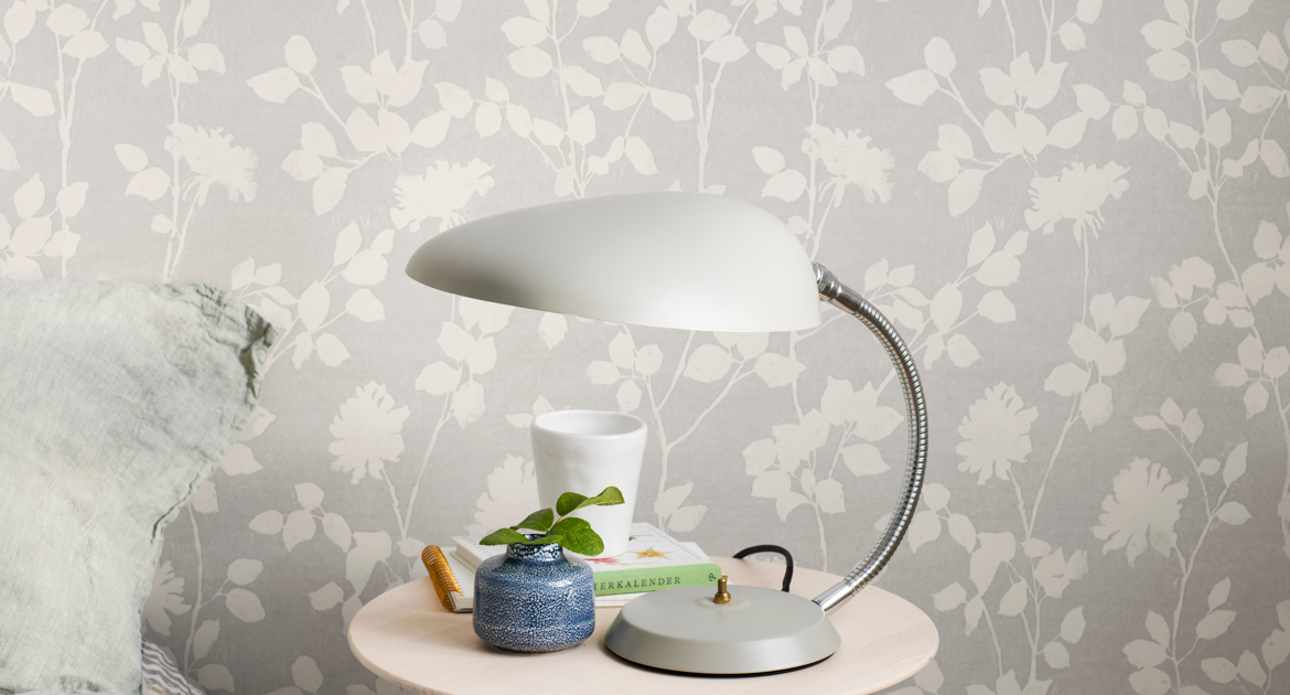 Närbild på blommig tapet och sovrumslampa