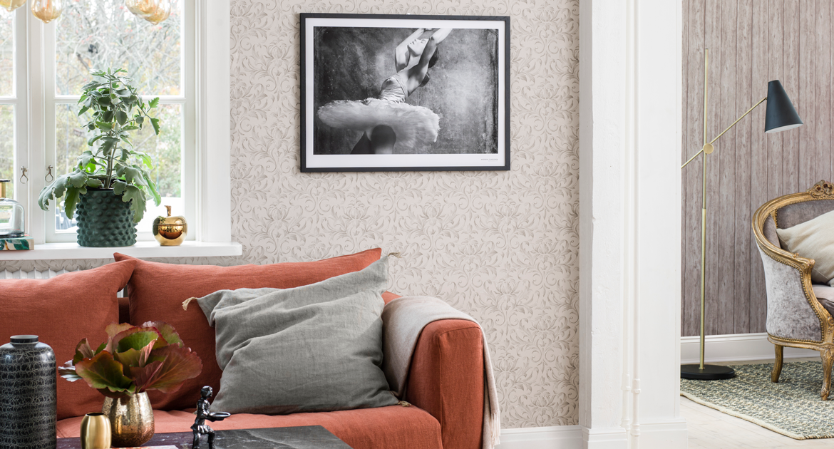 Vardagsrum med röd soffa och beigemönstrad tapet. Inspirationsbild.