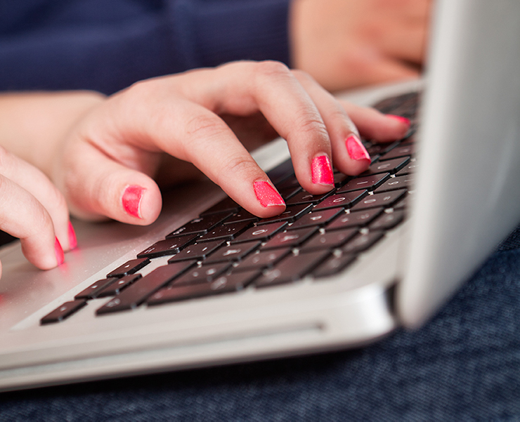 Händer skriver på tangentbord på bärbar dator.