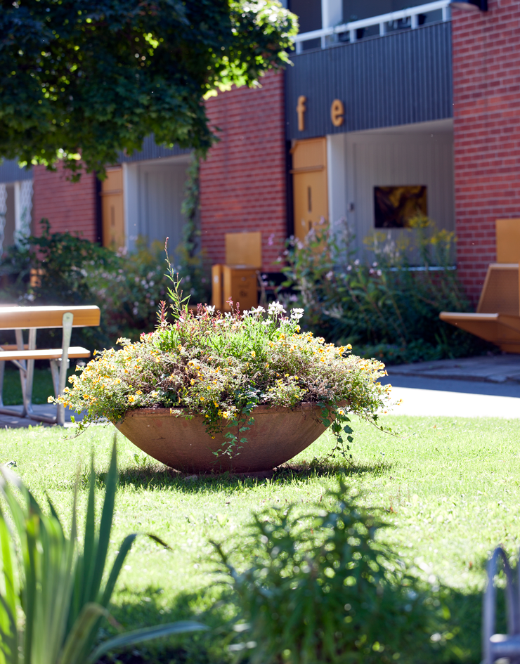 Gård i Brickebacken med stor odlingskruka och hus i bakgrunden.
