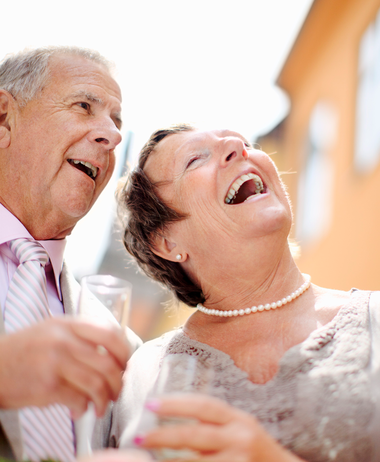 Äldre par är finklädda, skrattar och skålar