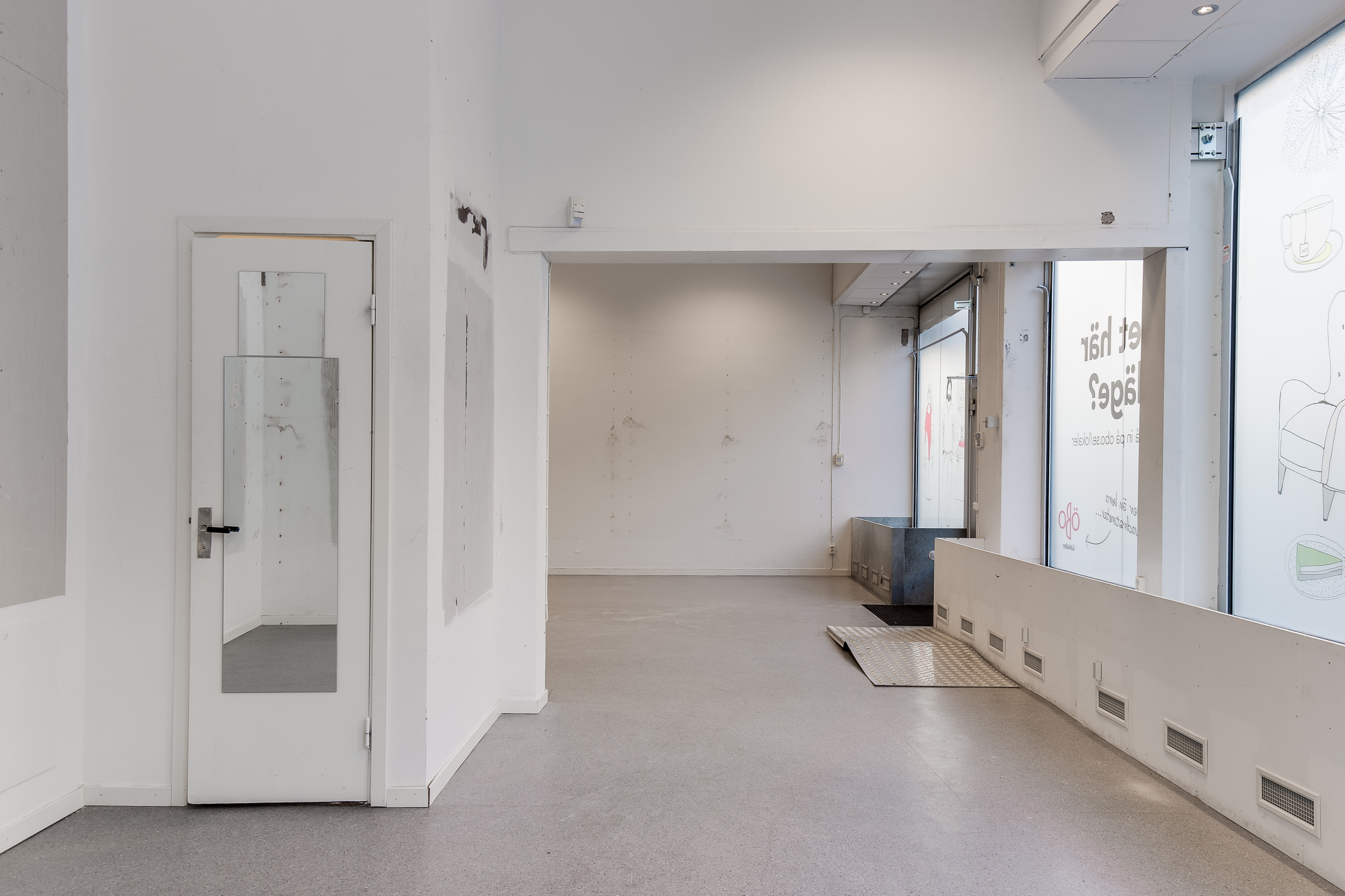 Del av butiksyta med stora skyltfönster och kundentré