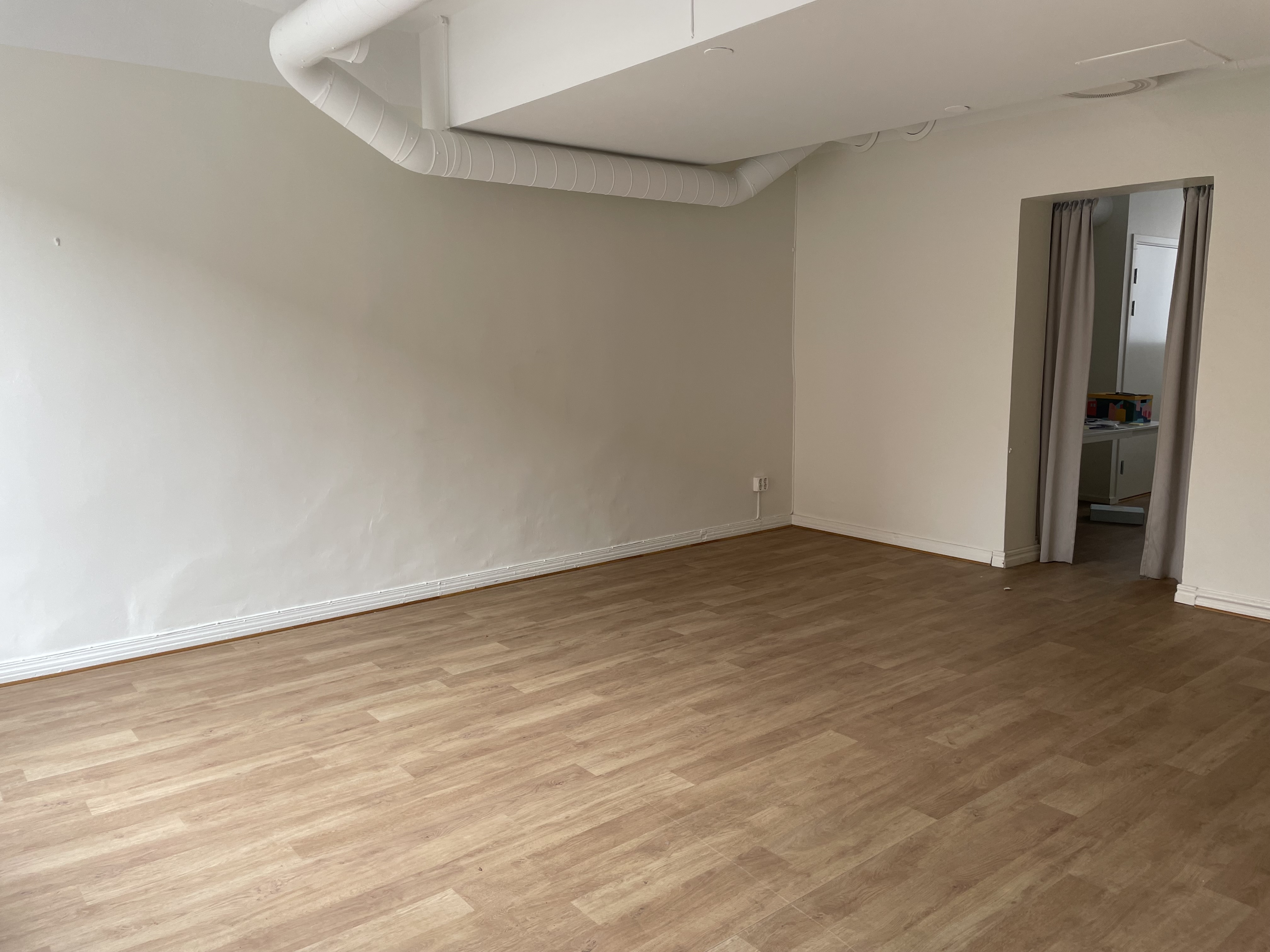 Del av lokal med parkettgolv och vita putsade väggar.