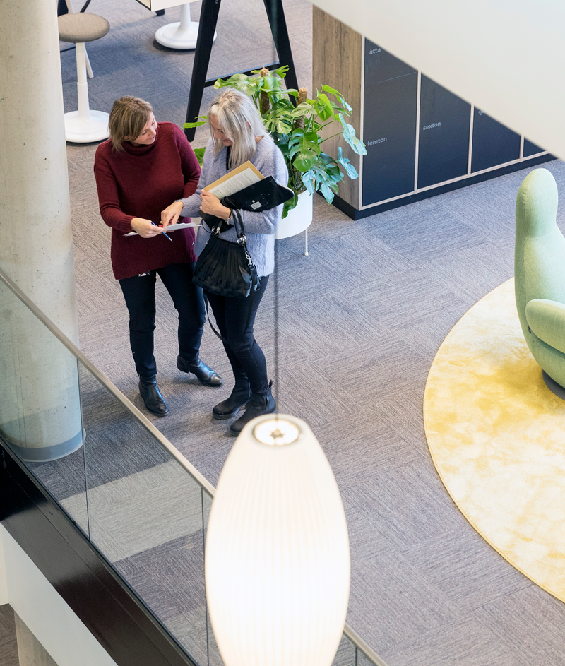 Två ÖBO-medarbetare på ÖBOs kontor pratar med varandra och tittar i ett papper