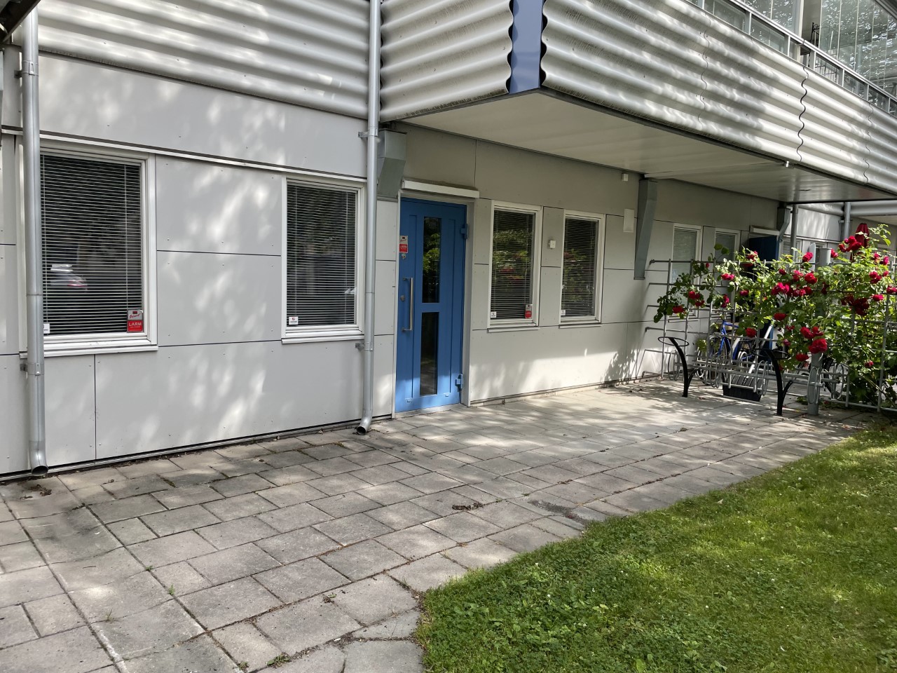 Entré till lokal i bottenplan på Idrottsvägen 16. Cykelställ och gräsmatta precis utanför dörren.
