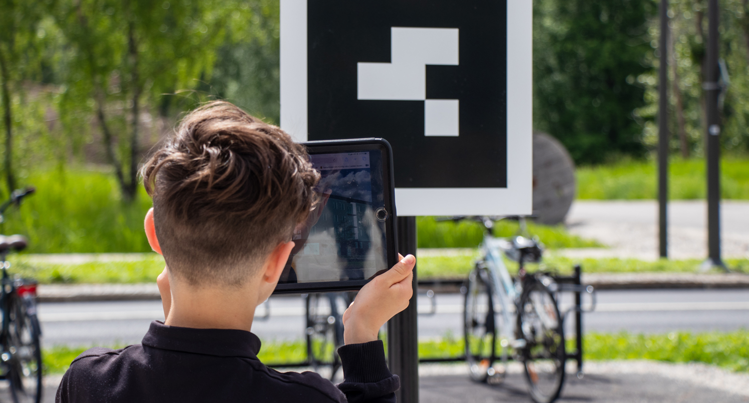 Pojke håller upp en surfplatta och tittar med hjälp av AR-teknik på hur Tamarinen planeras för att se ut.